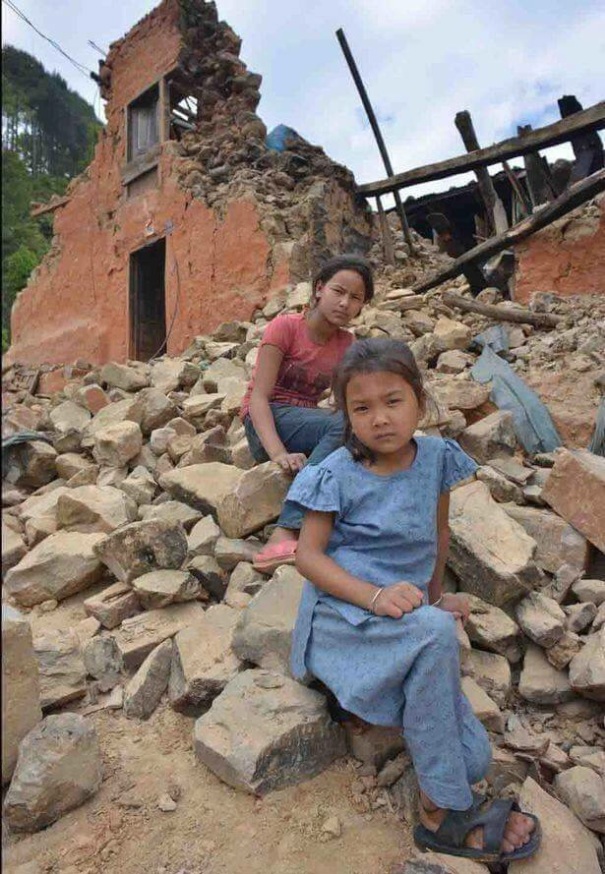 TWO GIRLS IN RUBBLE OF THEIR HOUSE